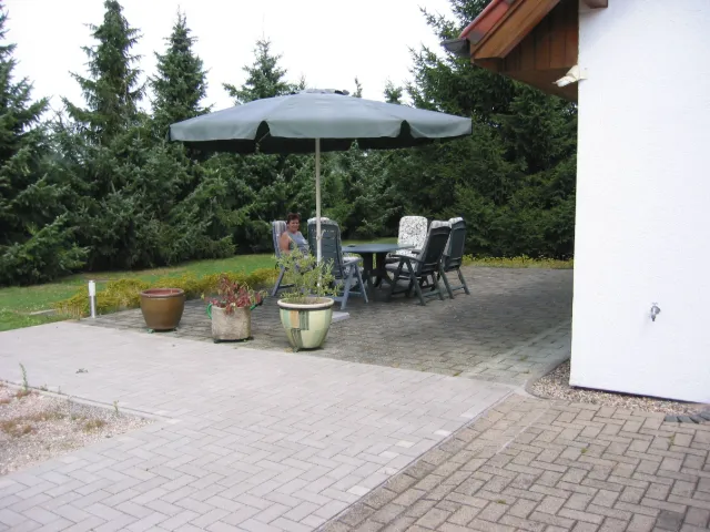 Gepflasterter Sitzplatz mit Sonnenschirm im Garten