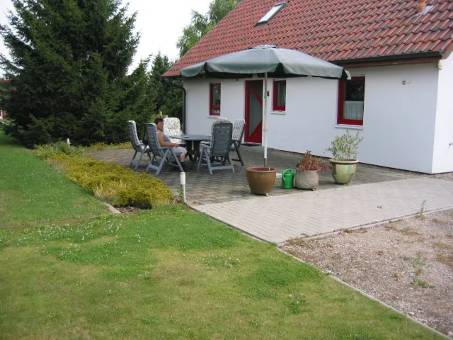 Terrasse mit Gartenmöbeln und Sonnenschirm am Haus