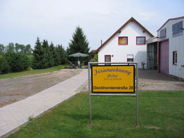 Einfahrt zum Hof mit dem gelben Schild der Ferienwohnung