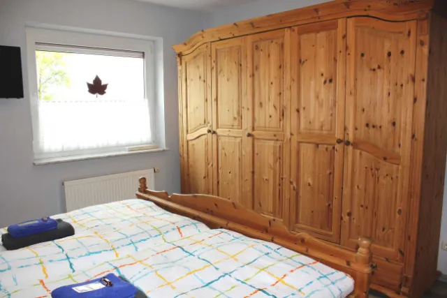 Schlafzimmer mit Doppelbett und großem Holzkleiderschrank